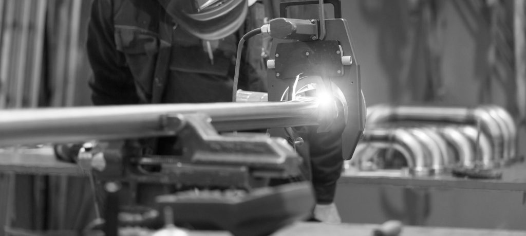 Welder TIG welding a stainless steel pipe with a precise, even weld seam